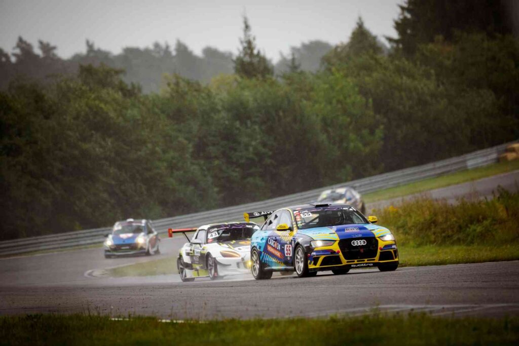 Permainingi orai šeštadienį Kačerginės „Nemuno žiede“ iš pradžių tik pagyvino „Ring Challenge“ varžybas, tačiau vėliau situacija tapo pernelyg pavojinga. Trasą užklojus lapais, šakomis ir žemėmis, pradėjus virsti medžiams bei griūti daliai infrastruktūros, organizatoriai priėmė sprendimą varžybas nutraukti. Vis dėlto iki audros sportininkai spėjo surengti du sprinto važiavimus ir kelias „Time Attack“ sesijas. Iki stipriausios audros dalies lietus lenktynininkams kėlė daugiau taktinių galvosūkių nei realaus pavojaus. Trasa tai džiūvo, tai vėl šlapo, todėl tinkamų padangų pasirinkimas tapo viena svarbiausių užduočių. Situacija smarkiai pasikeitė vėliau, kai lietų pakeitė stiprus škvalas. Vėjas pradėjo versti medžius, niokoti teisėjų bokštelius ir kitą trasos infrastruktūrą, dingo elektra. Virstantis medis vos nekliudė administracinio pastato Vienas medis nuvirto visai šalia šiemet renovuoto „Nemuno žiedo“ administracinio pastato. Žmonių tuo metu aplink nebuvo, o pats medis apie pavojų perspėjo pradėjęs skilti. Tuo metu dalyviai jau gaudė ir tvirtino vėjo blaškomas palapines, o organizatorių komanda ardė nugriuvusią renginio arką. Po audros dalis trasos atrodė tarsi po bekelės varžybų – asfalto dangą užklojo šakos, lapai, žemės ir kitos nuolaužos. Organizatorių vertinimu, vien trasai išvalyti ir paruošti būtų prireikę maždaug pusdienio. „Sprendimą priėmėme dėl saugumo. Oro sąlygos buvo pavojingos tiek dirbantiems trasoje, tiek joje važiuojantiems, be to, audra taip išdarkė trasą, kad iki vakaro jos nebūtume sutvarkę. Orų neužsakysi, bet labai pradžiugino lenktynininkų bendruomenė. Sustabdžius varžybas jie viską suprato ir netgi padėjo šalinti stichijos padarinius. Didelis ačiū jiems“, – sakė „Ring Challenge“ organizatorė Ugnė Rukšėnaitė. Lietus sumaišė kortas dar prieš audrą Iki varžybų nutraukimo sportininkai spėjo surengti du sprinto važiavimus ir kelias „Time Attack“ sesijas. PRO grupės sprinto lenktynėse lyti pradėjo dar apšilimo rate. Iš pirmosios pozicijos turėjęs startuoti Ramūnas Čapkauskas su „Lamborghini Huracan ST Evo“ prieš formavimo ratą pasuko į techninio aptarnavimo zoną ir automobilį „apavė“ lietaus padangomis. Dėl to startuoti jam teko iš rikiuotės galo, tačiau stiprėjantis lietus šį sprendimą pavertė privalumu. R. Čapkauskas greitai atsikovojo prarastas pozicijas ir GT klasėje finišavo pirmas. Antrąją vietą užėmė visais ratais varomą „Audi“ vairavęs Karolis Blėdis, trečias liko Aurimas Urbonavičius su „Ginetta“. RB3000 klasėje triumfavo Agnius Narbutas su „Honda S2000“, o BMW2500 įskaitoje greičiausias buvo Laimonas Starkevičius. Pusę lenktynių – tik su penkta pavara Dar daugiau veiksmo netrūko pirmojoje sprinto grupėje, kur tarpusavyje kovojo BMW automobiliais važiavę Gintaras Čepulis, Paulius Noreika, Arnoldas Pukys, Jordanas Kubilius, Mykolas Paulius ir Alanas Azikejevas. Pirmieji keturi sportininkai pozicijomis keitėsi po kelis kartus per ratą. J. Kubilius iš kovos dėl lyderio pozicijų pasitraukė trumpam išlėkęs iš trasos, o paskutinius ratus pirmavęs A. Pukys taip pat suklydo. Pergalė atiteko G. Čepuliui, nors maždaug pusę lenktynių jo BMW teko važiuoti tik penkta pavara. „Meldžiausi, kad tik neišmuštų pavaros, bet, matyt, tai stabilizavo mano situaciją. Turėjau daugiau galvoti apie patį važiavimą, ir besikeičiančiomis sąlygomis tai kaip tik padėjo, o ne pakenkė. Dabar reikia pabandyti susiremontuoti iki antro sprinto starto“, – iškart po finišo pasakojo G. Čepulis. Antrojo važiavimo surengti taip ir nepavyko. Įsisiautėjus audrai jis buvo atšauktas, todėl G. Čepulis tapo etapo nugalėtoju ir kartu gavo gerokai daugiau laiko pavarų dėžei remontuoti. Greičiausias – R. Čapkauskas su „Lamborghini“ „Time Attack“ dalyviams taip pat teko taikytis prie nuolat besikeičiančios trasos būklės. Greičiausią dienos rezultatą džiūstančioje trasoje užfiksavo R. Čapkauskas. Su „Lamborghini“ jis 3,335 km ilgio „Nemuno žiedo“ ratą įveikė per 1 min. 8,049 sek. PRO GT klasės nugalėtojui šios varžybos kartu tapo proga išbandyti automobilį po remonto. PRO2000 klasėje nugalėjo A. Narbutas su „Honda S2000“, ratą įveikęs per 1 min. 16,759 sek. PRO3000 klasėje greičiausias buvo Artūras Kliobavičius su BMW – jo rezultatas 1 min. 14,409 sek. Kitų klasių dalyviai važiavo kiek lėtesne trasos konfigūracija su dviem papildomomis greičio mažinimo zonomis pavojingiausiose vietose. SGC4 klasėje nugalėjo Darius Vasiliauskas su „Chevrolet Corvette“, užfiksavęs 1 min. 20,441 sek. rezultatą. SGC3 įskaitoje greičiausias buvo Darius Kliaudaitis su „Toyota GR Yaris“ – 1 min. 22,201 sek., o SGC2 klasėje Saulius Bučius su „Peugeot 206 RC“ ratą įveikė per 1 min. 27,944 sek. Lengvai modifikuotų automobilių OC3 kategorijoje laimėjo Grantas Mackevičius su BMW – 1 min. 21,317 sek. OC4 klasėje pirmąją savo pergalę „Time Attack“ varžybose iškovojo Augustė Rupšytė su „Volkswagen Golf“, ratą įveikusi per 1 min. 27,851 sek. Istorinių automobilių įskaitoje greičiausias buvo Vėjūnas Toleikis su penktos kartos „Honda Civic“. Jo rezultatas – 1 min. 32,326 sek. Finalinis šių metų „Ring Challenge“ etapas numatytas spalio 17 dieną Kačerginės „Nemuno žiede“. Jame sportininkų lauks ne tik paskutinės sezono kovos, bet ir naktinės „Endurance“ lenktynės.